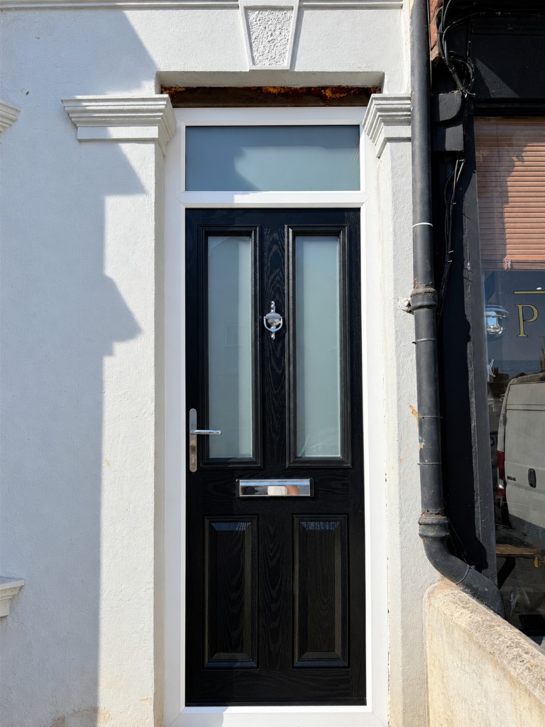 Black front door with frosted glass panels and chrome handle in a white frame