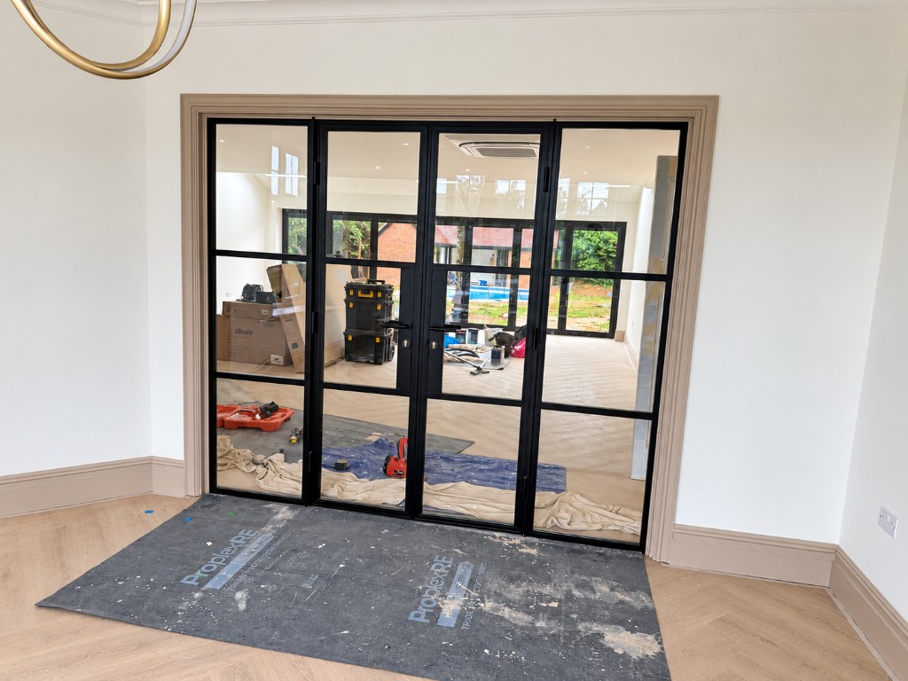 Black Crittall-style internal glass doors with herringbone flooring beyond